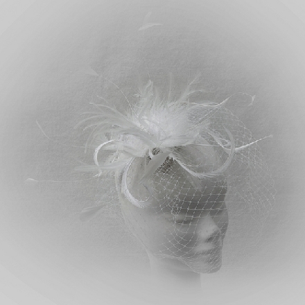 A feminine ivory white feather fascinator with crystals, pearls and veil, perfect for brides.
